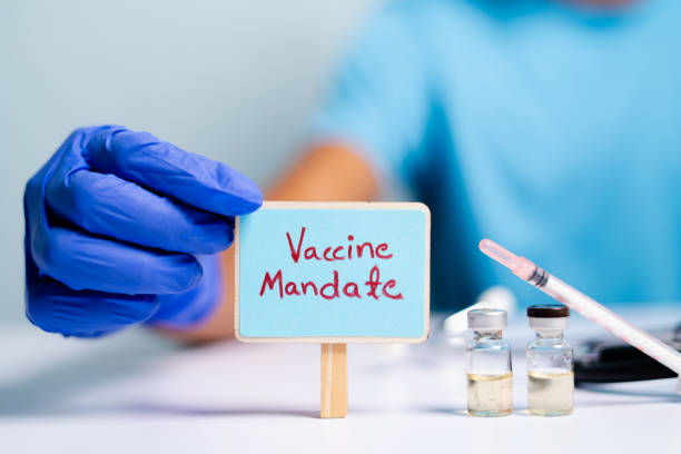 Concept of coronavirus or covid-19 vaccine mandate, showing with doctor hands with gloves by placing sign board next to vaccine shots and syringe Concept of coronavirus or covid-19 vaccine mandate, showing with doctor hands with gloves by placing sign board next to vaccine shots and syringe. vaccination stock pictures, royalty-free photos & images