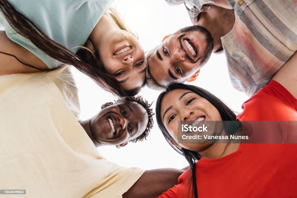 Group of diverse friends hugging in circle - Happy people having fun outdoor - Main focus in gay man face Indigenous Peoples of the Americas Stock Photo