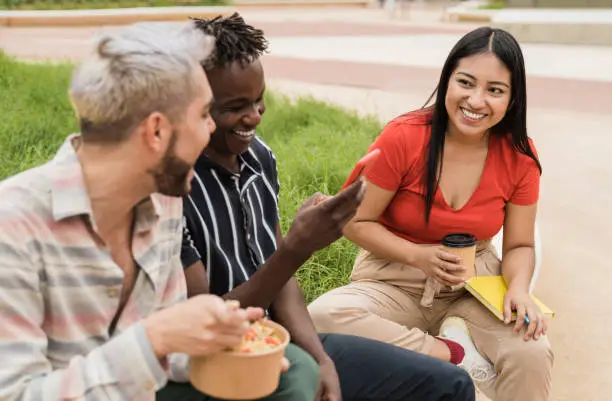 Photo of Happy friends having fun eating take away food outdoor in the city - Focus on asian girl face