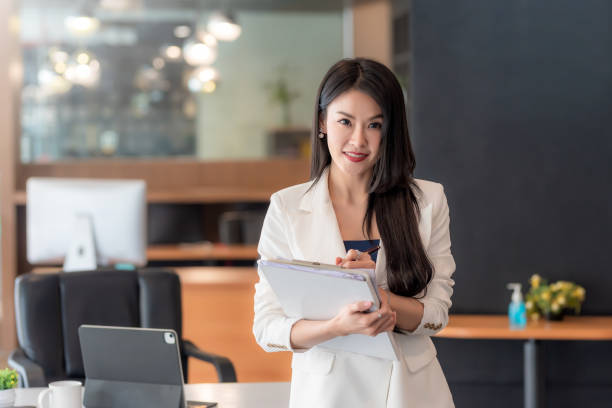 istock Charming businesswoman standing with documents at the office. Looking at camera 1342450737