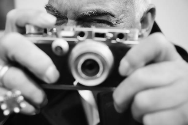 The photographer. beautiful senior man, vintage, camera, photographing, glamour, retro style, sensuality, fun, elegance, human face, close-up, journalist, paparazzi, black and white portrait photographers stock pictures, royalty-free photos & images