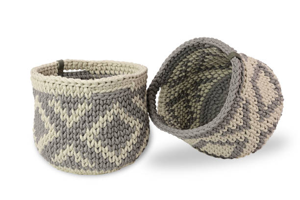 istock Two crocheted baskets with a mirror pattern made of thick yarn. One basket is slightly inclined leaning against another 1342455078