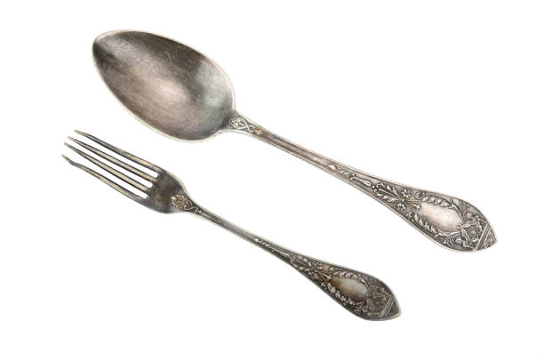 Top view of a tablespoon and fork with embossed patterns on the handles. Both are from one set. Isolated on white background.