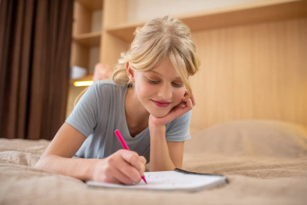 istock A girl lying on the bed and writing something in a notebook 1342457782