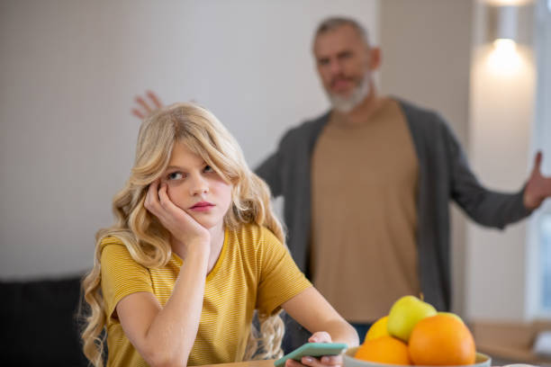 A blonde cute girl feeling frustrated while her father shouting at her stock photo