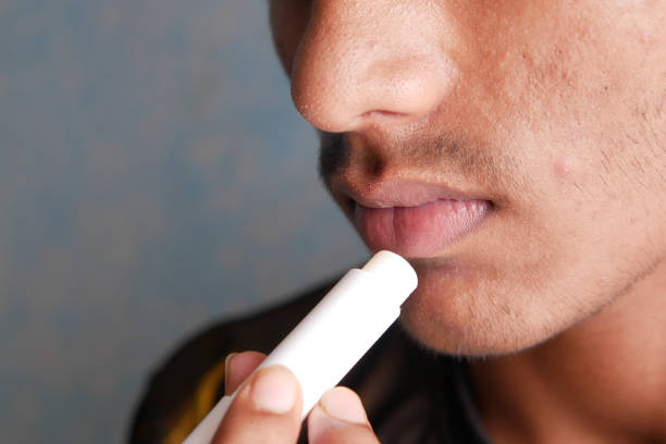 istock young man applying moisturising lip balm on lips 1342459064
