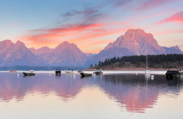 Overview of Jackson Lake with colorful boats in foreground before sun rise viewing from signal Mountain campground at Grand Teton National Park, Wyoming USA.