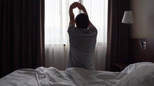 istock Silhouette of man sitting on bed stretching up arms 1342462616