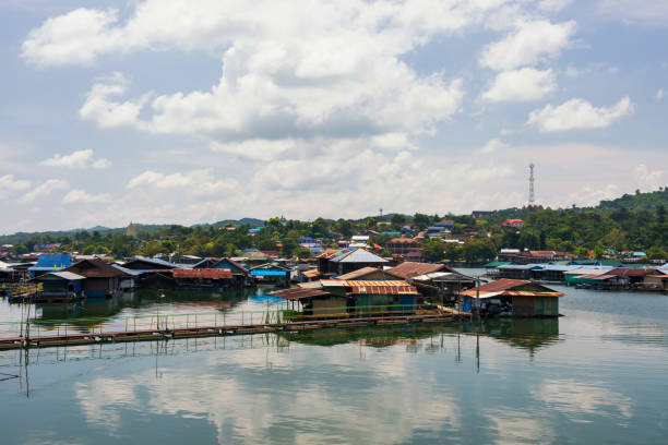 Floating raft house village near Mon wooden bridge and and Buddhakhaya golden pagoda, Sangkhlaburi, Kanchanaburi, Thailand. landscape with skyline reflection on water river.