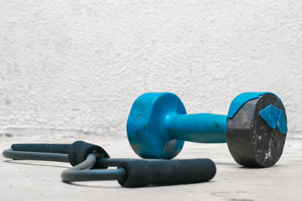 istock Second hand blue dumbbell, next to resistance band (used, rusty) white background, exercise at home, space for text. exercise and health concept. fitness concept 1342471397