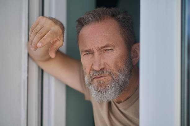 istock Despondent mature person standing by the window 1342474083