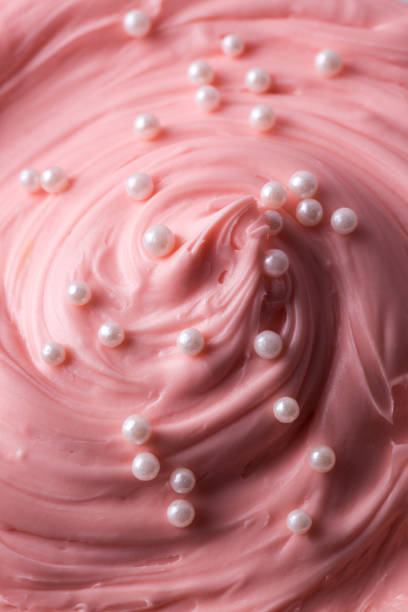 istock Pink icing frosting with small pearl sprinkles close up texture 1342474938