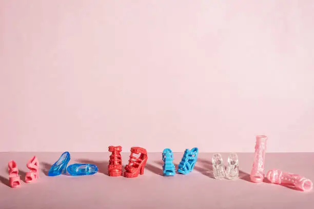 Six  pairs of toy shoes in a row on a pink background