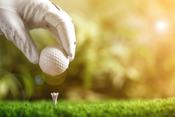 joueur mettant une balle de golf sur le tee dans un parc d’été ensoleillé, gros plan. espace pour le design - golf golf club golf swing tee photos et images de collection