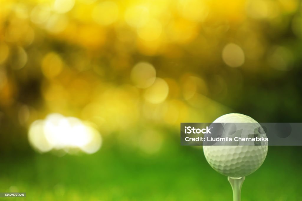Golf ball on tee in sunny summer park. Space for design Golf Stock Photo