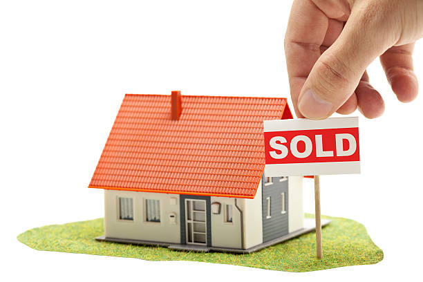 Sold house Hand holding "sold"-sign in front of model house - real estate buying concept sell my house stock pictures, royalty-free photos & images