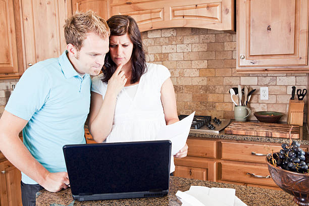 istock Young Couple in Kitchen Paying Bills Online 134248127