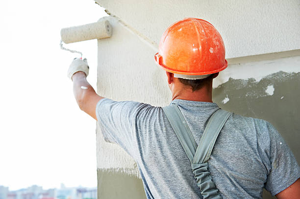 Construction working putting plaster on a wall Young painting facade builder worker with roller at thermal insulation works facade stock pictures, royalty-free photos & images