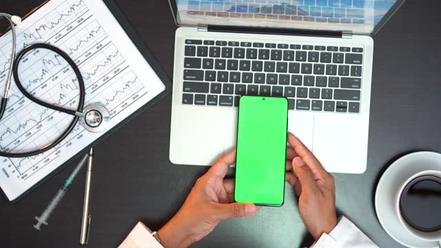 Consulting physician scrolling green screen of smartphone, viewing test results