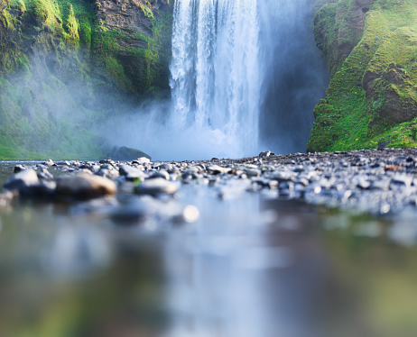 Skogafoss waterfall, Iceland. Mountain valley and reflection on the water surface. Natural landscape in summer season. Icelandic nature. Travel image