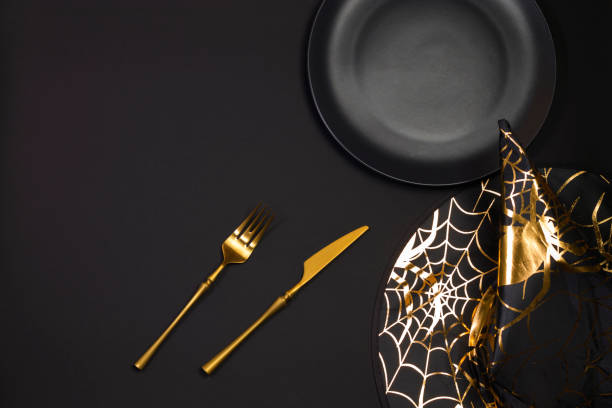 istock Halloween table setting. A platter on a dark table with a black pointed conical witch hat. Flat lay, top view trendy holiday concept. Copy space 1342492164