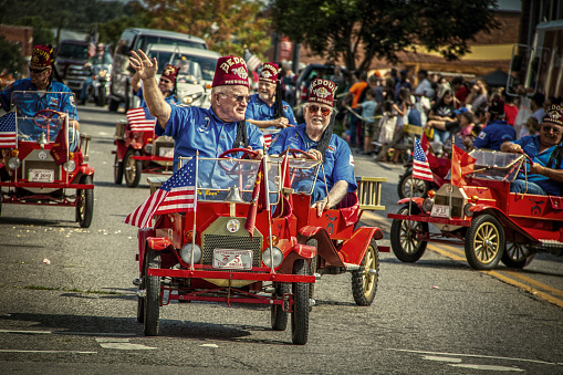 2019_08_31_Tahlequah USA Bedouin Shriners Fire Brigade - old men in mini firetrucks with American flags in Main Street Parade