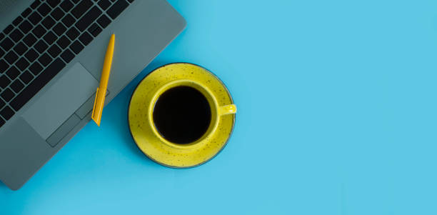 istock cup of coffee, laptop on a colored background 1342495874