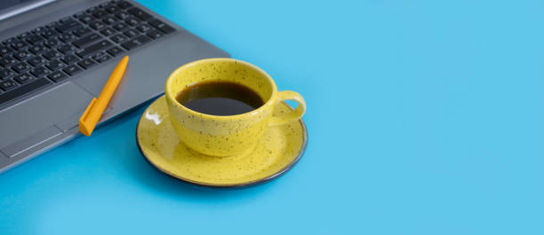 istock cup of coffee, laptop on a colored background 1342497206
