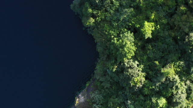 A top down shot above an abandon rock quarry, in Verplanck, NY, filled with beautiful green waters, taken on a sunny day with a drone.