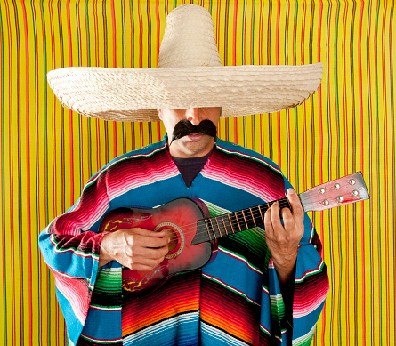 Mexican man serape poncho sombrero playing guitar typical Mexico