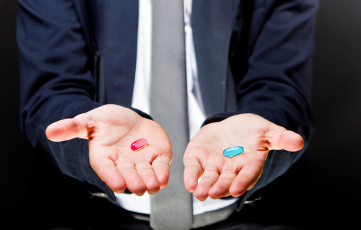 Man showing blue pill in one hand and red pill in the other