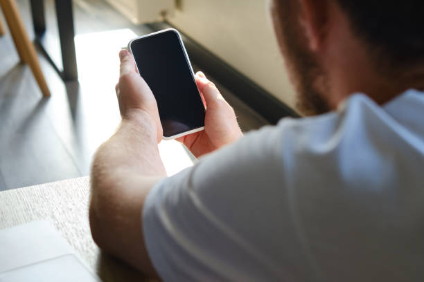 istock A man is holding a modern smartphone, sending a text message or using an application on his mobile phone. Business concept. Smartphone close-up. Focus on the phone screen 1342498579