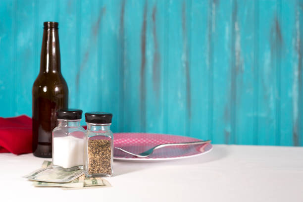 A glass jar with a green lid filled with salt. The jar stands on a checkered red and white tablecloth.