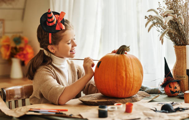 istock Smiling little kids girl making jack-o-lantern at home, drawing 1342500549