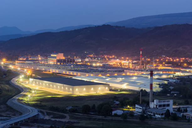 освещенная современная фабрика и старый, разрушенный завод ночной вид сверху - огромные smoky горы стоковые фото и изображения