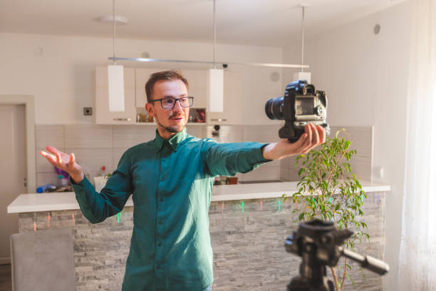 istock Young white male with glasses vlogging with a professional DSLR camera while explaining something 1342502366