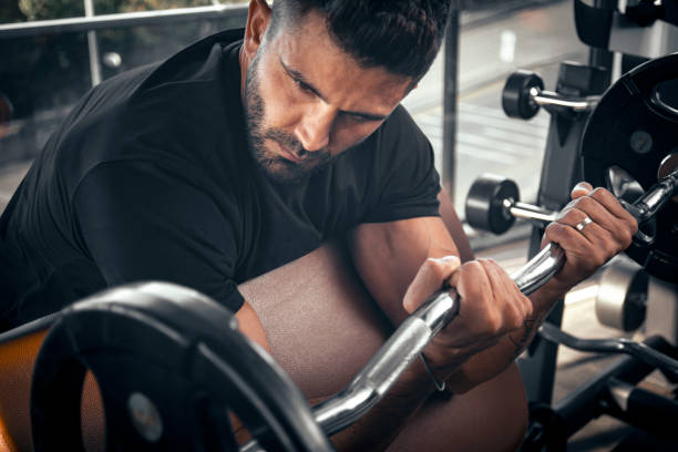 A man doing arm workout with barbell at gym. Barbell biceps curl exercise A man doing arm workout with barbell at gym. Barbell biceps curl exercise bicep curl ripl fitness