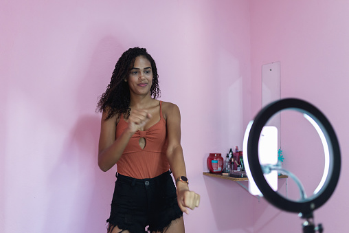 Joven negra filmándose a sí misma bailando en casa para compartir en las redes sociales photo
