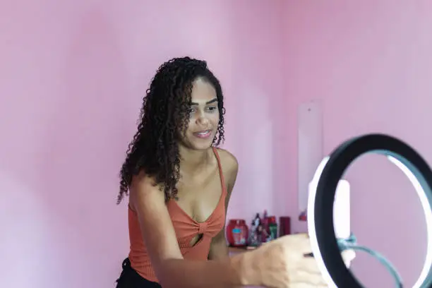 Photo of Black young woman filming herself dancing at home to share on social media