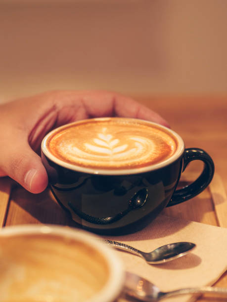 istock Man's hand drinking a cup of coffee with milk 1342509902