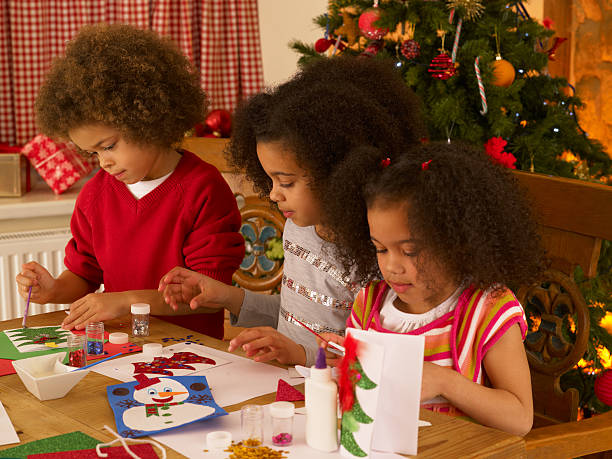 Mixed race children making Christmas cards stock photo