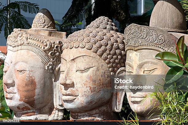 Foto de Três Cabeças De Buda De Pedra De Sentarse Ao Lado Umas Das Outras Entre Árvores e mais fotos de stock de Estátua