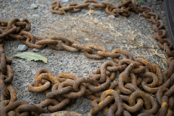 Macro of thick rusted chain on concrete. Outdoor photo of rusty equipment.
