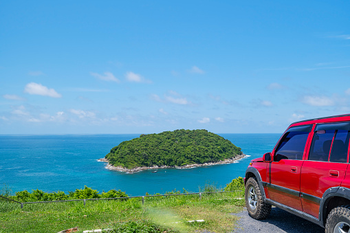 Red SUV 4x4 car on the mountain with Summer sea and small island background of free space for summer text and travel transportation background.