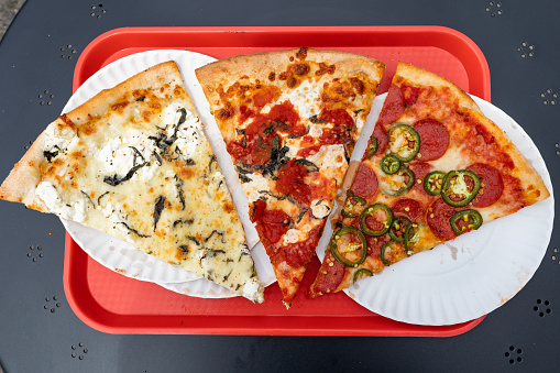 An overhead view of three New York City style pizza slices on a red tray