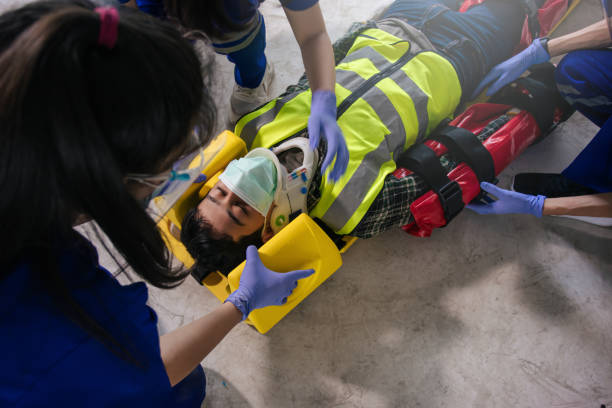 team ems sanitäter erste hilfe bei kopfverletzungen. sanitäterteam erste-hilfe-bauunfall bei der baustellenarbeit. - krankenhausbahre stock-fotos und bilder