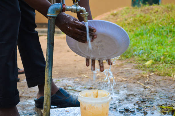 istock Young man's hands cleaning dishes with water tap 1342602234