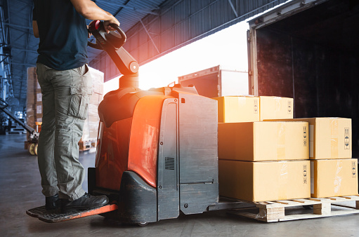 Forklift Driver Loading Package Boxes into Cargo Container at Dock Warehouse. Delivery Service. Shipping Warehouse Logistics. Cargo Shipment. Freight Truck Transportation.