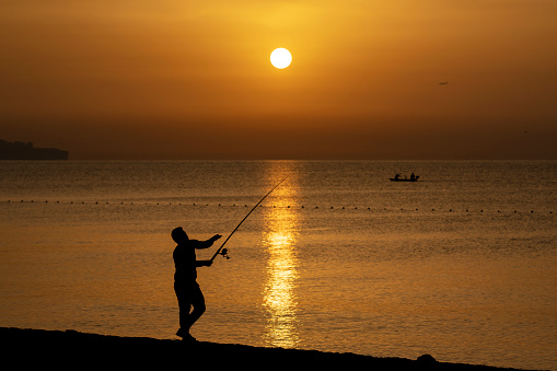 Fisherman fishing on the beach at sunrise, Konyaalti Beach, Antalya, Turkey