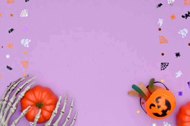 istock Halloween background with skeleton hands hold a pumpkin and candy bucket. 1342610123